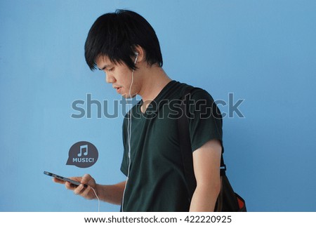 The guy is using a smart phone to listen music with headphones  - blue background

