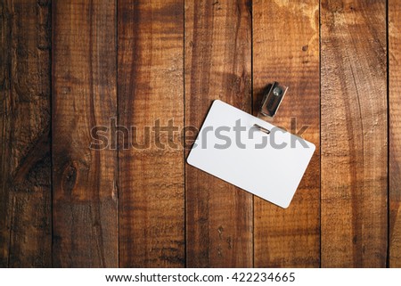 Blank badge on vintage wooden background. Blank plastic id card. Blank white plastic badge. Top view.