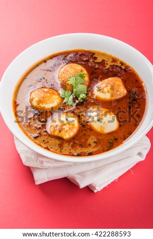 Anda Curry or Egg masala gravy is popular indian spicy food or recipe, One portion served in a ceramic bowl over colourful or wooden table top. Selective focus.
