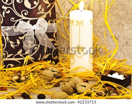 Photo of holiday decoration with gift box, candles and nuts against beige background