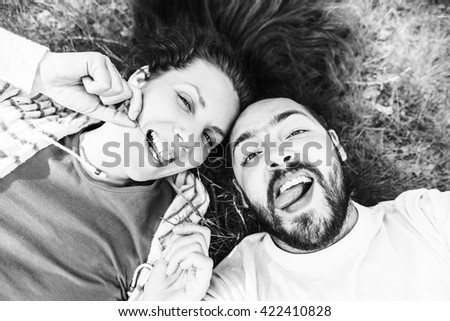 Handsome man with beard and young pretty cheerful girl with glasses making selfie in nature