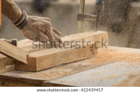 Handmade and craft furniture concept: Carpenter engaged in processing wood at the sawmill Royalty-Free Stock Photo #422439457