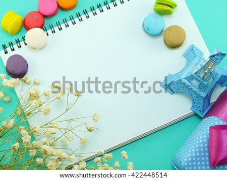 top view of macaroons flowers and souvenir eiffel tower with diary copy space background