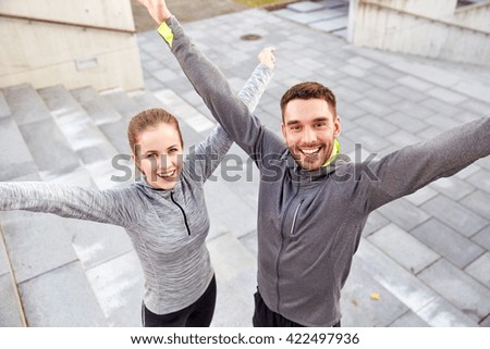 fitness, sport, people and lifestyle concept - happy smiling couple outdoors on city street Royalty-Free Stock Photo #422497936