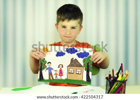Cute child holds up drawing of a family