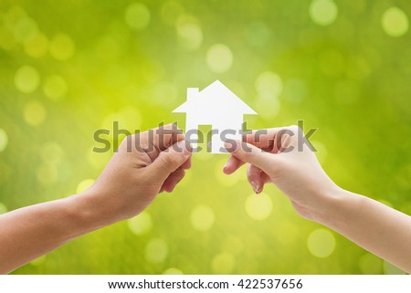 Hand holding house on green background