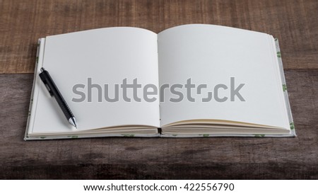 Closeup of opened handmade book and pencil on wooden background