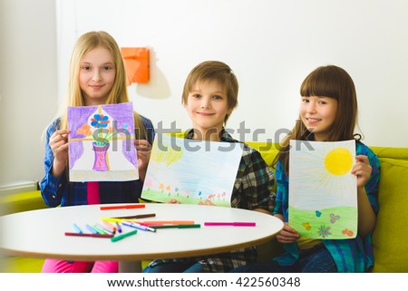happy children show their pictures drawn. Indoor at room