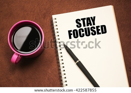 stay focused - text on notebook with a pen and cup of coffee