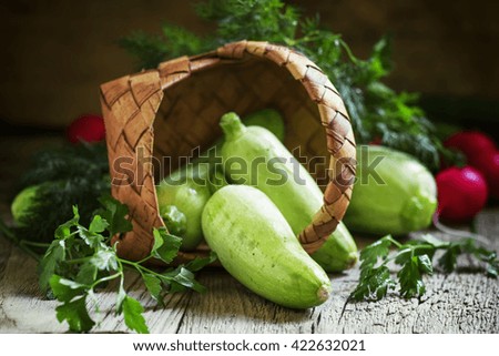 Fresh small zucchini, poured out of a wicker basket, vintage wooden background, shallow depth of field