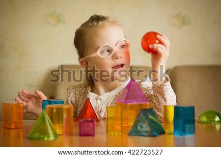 Girl with Down syndrome playing with geometrical shapes Royalty-Free Stock Photo #422723527