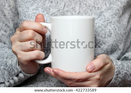 Girl is holding white cup in hands. Mug for woman, gift. Mockup for designs. Royalty-Free Stock Photo #422733589