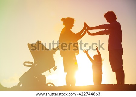 Happy family with child and pregnant mother together at sunset