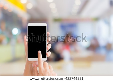 woman use mobile phone and blurred image of people in food court in the mall