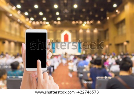 woman use mobile phone and blurred image of people in pre-school events in the hall