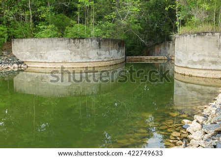 Countryside water reservoir within tropical rainforest surrounding. Private water catchment in the forest for clean water supply.