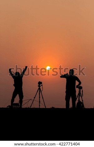 Silhouette photographers with sunset background