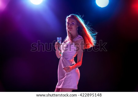 The beautiful girl dancing at the party drinking champagne