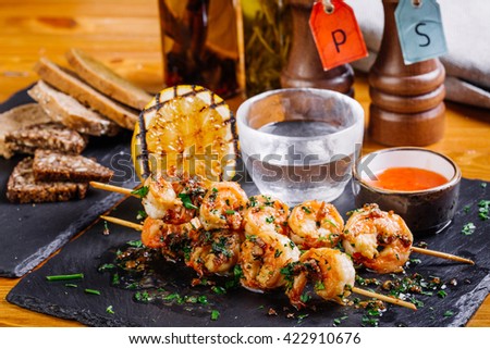 Delicious roasted shrimps on skewers with sauce and lemon