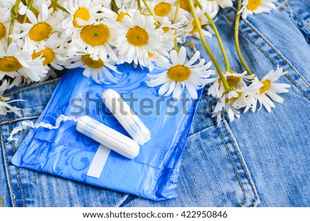 Woman hygiene protection, close-up.panty liners and tampons on jeans background.white daisy flowers, women's health.feminine pads.critical days