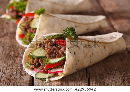 Burritos with minced meat and fresh vegetables close-up on the table. Horizontal
