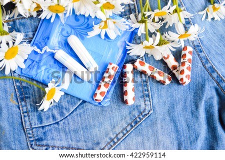 Woman hygiene protection, close-up.panty liners and tampons on jeans background.white daisy flowers, women's health.feminine pads.critical days