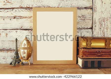 image of blank wooden frame, next to old books. template, ready to put photography. vintage filtered