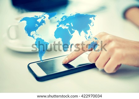 business, technology, global communication and people concept - close up of woman hand with smartphone and coffee pointing finger to screen over world map projection