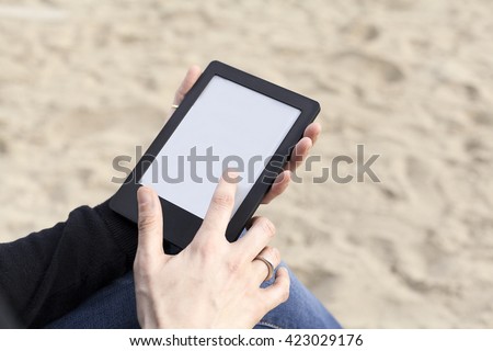woman hands holding and pointing a tablet at the beach