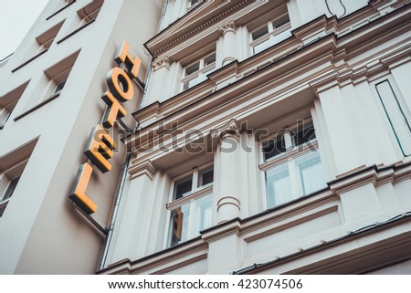 hotel sign in golden letters on white building