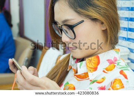 Beautiful young Asian happy with talking her friend and using smart phone