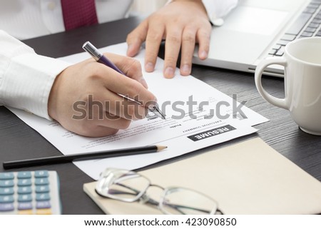 Business man review his resume on his desk, laptop computer, calculator
