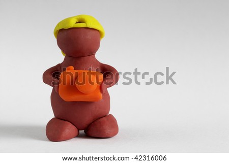 Plasticine man keeping the camera over grey gradient background