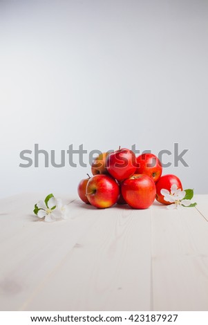 red apples on a white wood table with flowers