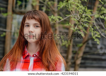 May 2016, set. Girl teenager in a red plaid shirt walking in the old courtyard, where the cherry trees bloom.