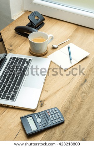 Working supplies and laptop with cup of coffee on wooden desk from above
