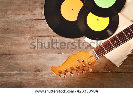 Guitar and gramophone records on wooden background