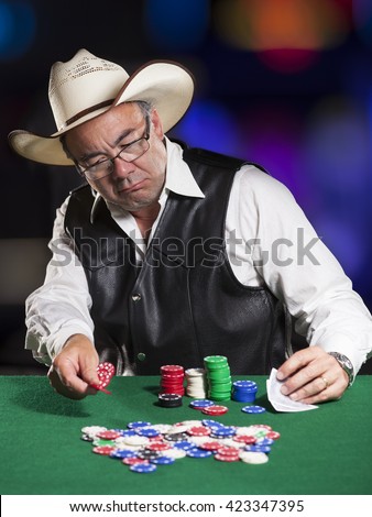 Funny male Asian poker player dressed as a cowboy with vest and hat.