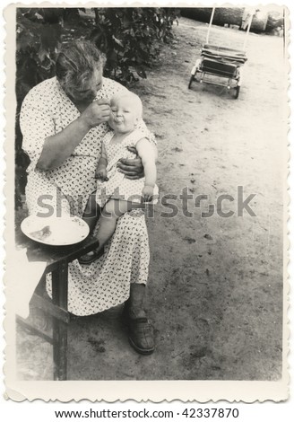 mother feeding a baby with a spoon. USSR 1950s 20 century