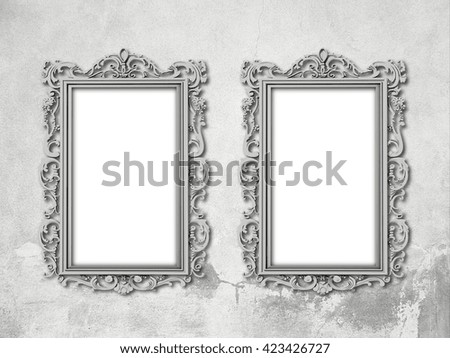 Close-up of two silver blank Baroque picture frames on gray concrete wall background