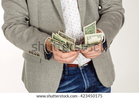 closeup portrait of young businessman holding and counts money dollar bills in hands, isolated on white background. emotion facial expression feeling. financial reward savings