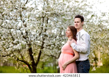 Couple in love under blooming branches spring day. Young adult brunette male and female kiss fresh Apple blossom and