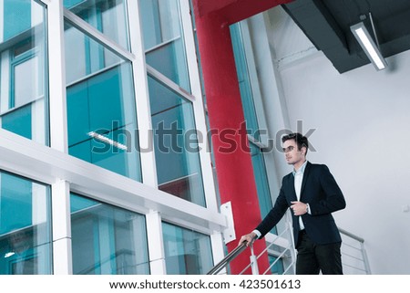 Future businessman after graduating standing in his old college and looking through the window