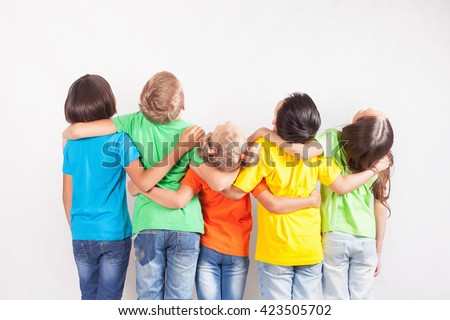 Group of multiracial funny children. Kids looking up at copy space with white background. Dressed in colorful T-shirts and jeans. Education, school
