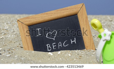 I love the beach written on a chalkboard in front of the sea