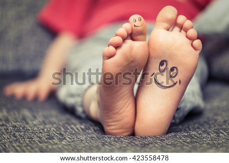 Concept of kids feet with smiley face drawing Royalty-Free Stock Photo #423558478
