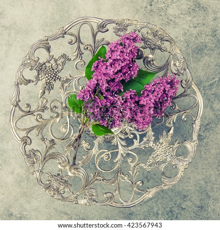 Lilac flowers and antique silver plate on stone background. Vintage style toned picture