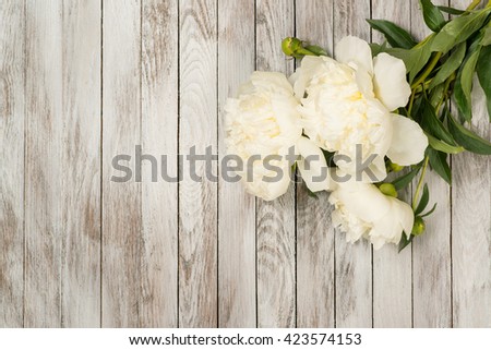White peonies flowers on the white painted wooden planks. Place for text. Square image. Top view.