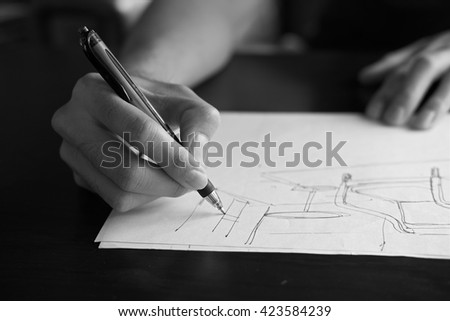 Hand of Designer with a pen, designing and sketching his idea in monochrome