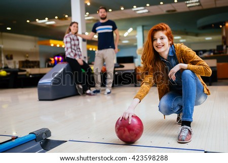 Beautiful woman bowling with friends getting ready to throw ball